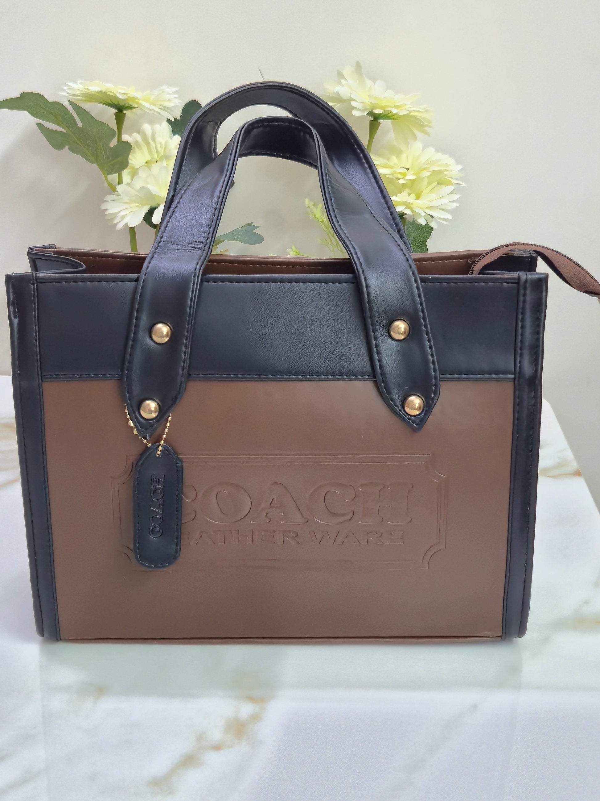 Brown leather-bound book with a black strap and gold hardware 